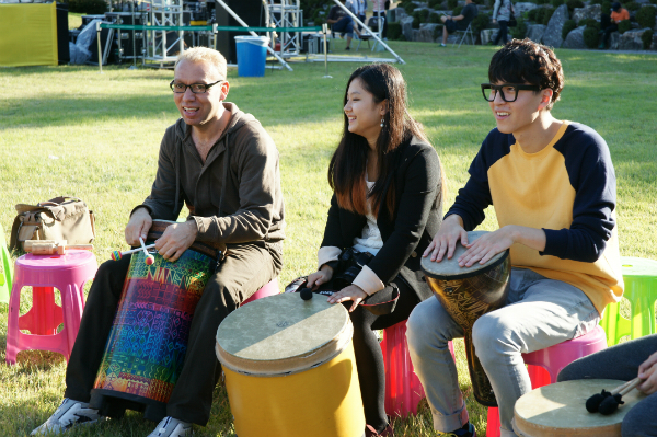 축제 참가자들이 세계 각국의 타악기를 두드리며, 홍캠프의 두그루 드럼서클을 즐기고 있다.